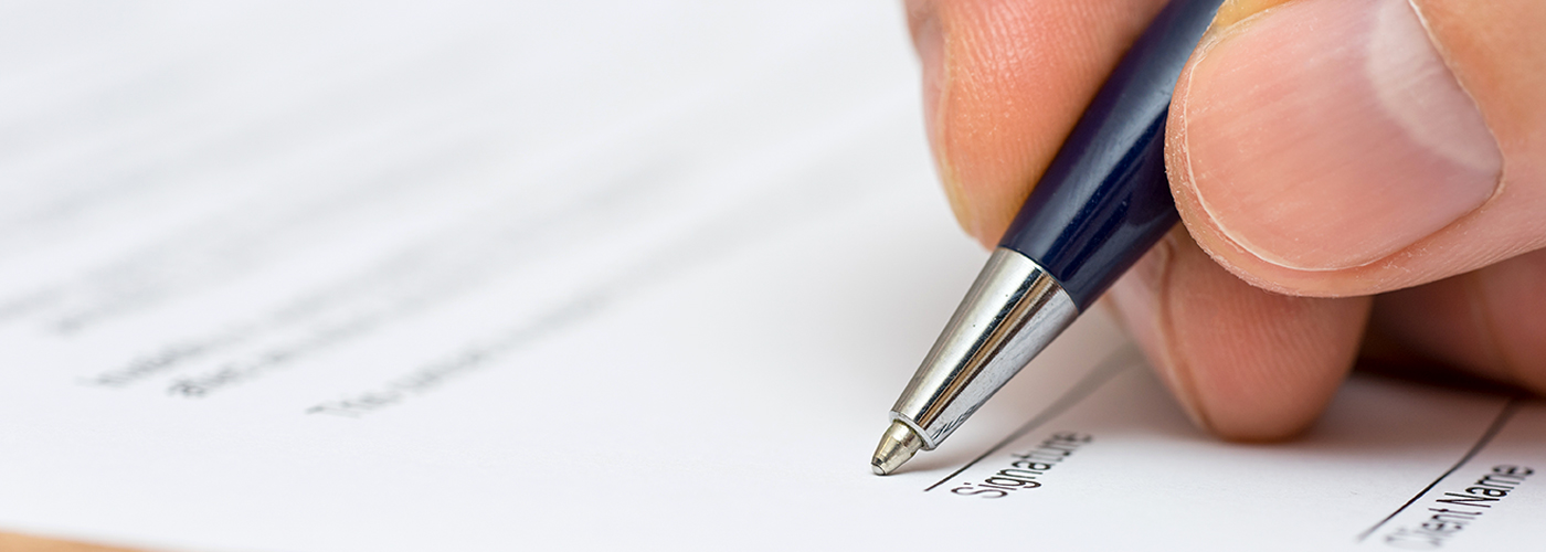 person-holding-pen-and-signing-document