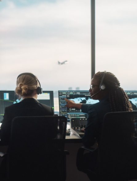 Two air traffic controllers in tower looking at radar